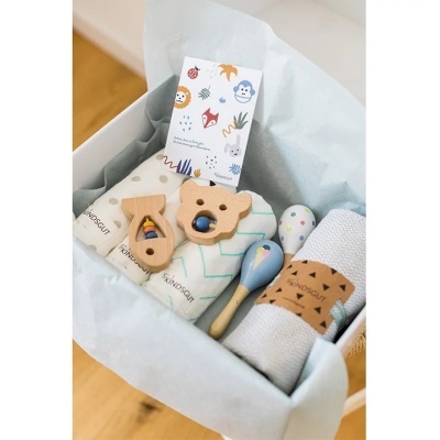 Cesto de presente com brinquedos e panos enrolados em caixa branca