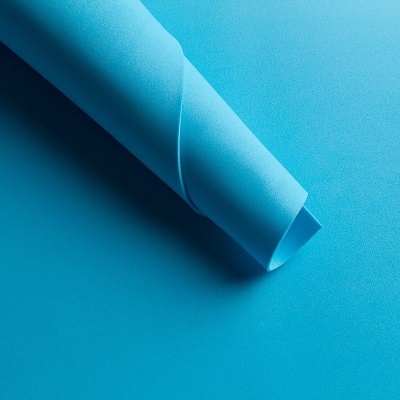 Folha de papel azul clara enrolada sobre fundo azul