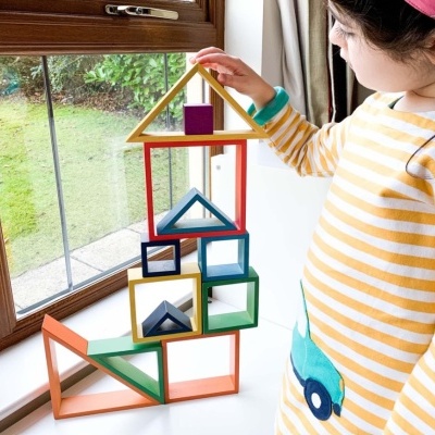 Brinquedo de empilhar de formas geométricas coloridas junto a criança perto de janela