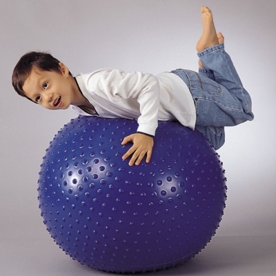 Criança deitada sobre uma bola de exercício azul com textura rugosa