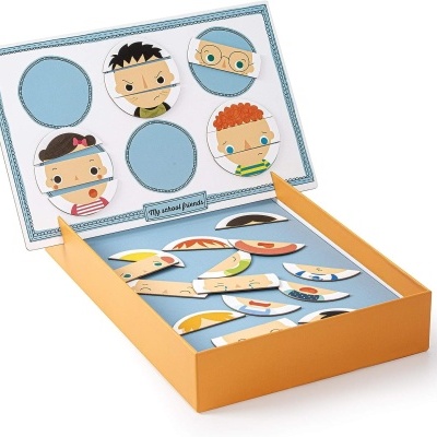 Peças magnéticas coloridas para montar rostos ilustrados numa caixa de cartão amarelo