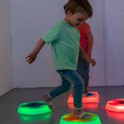 Crianças brincando com plataformas iluminadas no chão