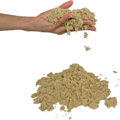 Mão a segurar areia cinzenta clara granulada a cair para um monte de areia.