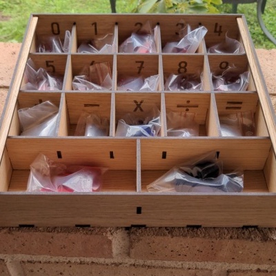 caixa de madeira com compartimentos e peças embaladas em sacos