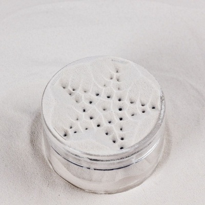 Recipiente de pó branco com tampa perfurada em padrão de estrela sobre fundo branco