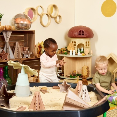 Mesa sensorial de areia com brinquedos e crianças a brincar