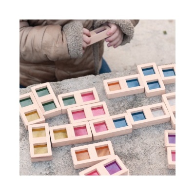 Peças coloridas de madeira retangulares e quadradas sobre pedra com criança ao fundo
