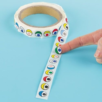 Rolo de autocolantes com olhos coloridos sobre fundo azul claro.