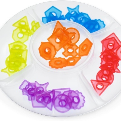 Prato branco com compartimentos separados com formas plásticas coloridas variadas.