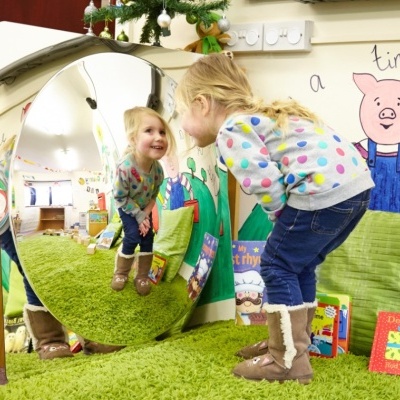 Espelho convexo circular na parede com criança sorridente e decoração infantil colorida