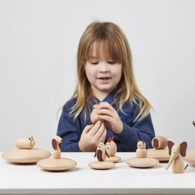 Criança com brinquedos de madeira em forma de animais sobre mesa branca