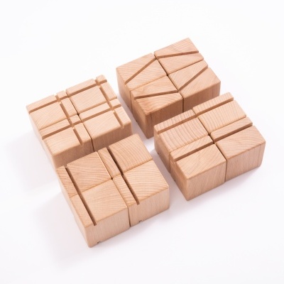 Quatro blocos de madeira clara com cortes geométricos distintos sobre fundo branco