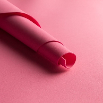 Material sintético rosa enrolado sobre superfície rosa