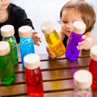 Frascos coloridos com tampas de madeira e crianças a interagir