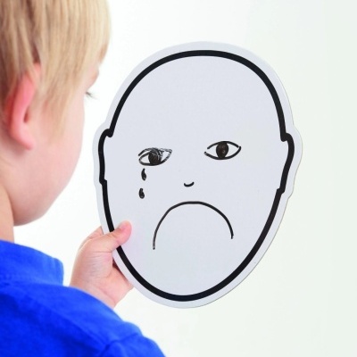 Criança a segurar máscara branca com rosto triste desenhado