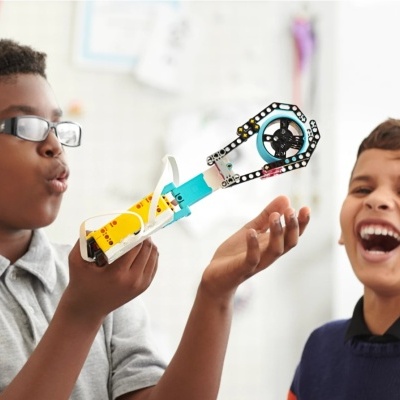 Crianças brincando com brinquedo de construção tipo LEGO com discos azuis