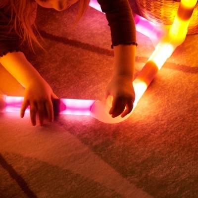 Criança a montar tubos luminosos modulares no chão
