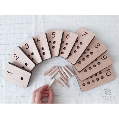 Peças de madeira numeradas de 1 a 10 com buracos e pinos de madeira sobre tecido branco