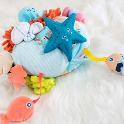 Brinquedo de tecido marinho colorido para bebé sobre fundo branco felpudo