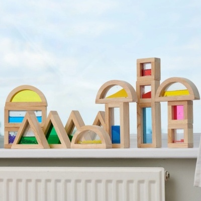 Blocos de construção de madeira coloridos alinhados numa superfície branca