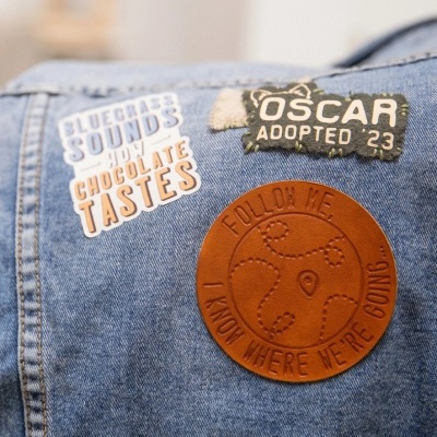 Casaco de ganga azul com três patches decorativos visíveis.