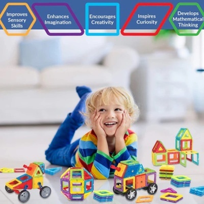 Criança loira deitada com blocos magnéticos coloridos no chão em sala com sofá ao fundo