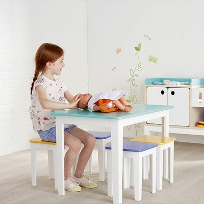 Mesa infantil com bancos e criança a brincar com boneca
