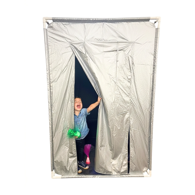 Tenda cinza com criança sorridente segurando objeto verde e luzes coloridas no interior