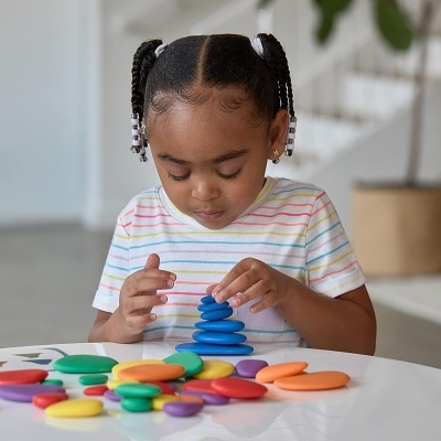 Criança a brincar com brinquedos coloridos em mesa branca