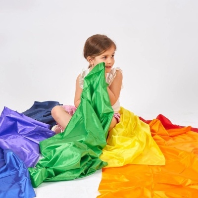 Criança sentada com tecidos coloridos no chão