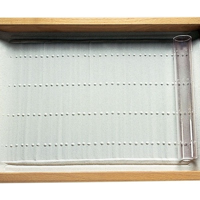 Tabuleiro de madeira com fundo branco furado e tubo de vidro