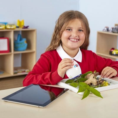 Criança a usar dispositivo em tabuleiro com plantas e cogumelos numa mesa com tablet