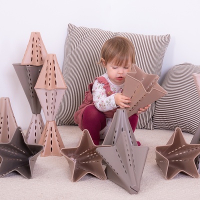 Criança brincando com construção de estrelas e cones em tons castanhos