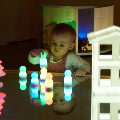 Bebé a brincar com figuras luminosas coloridas sobre uma superfície reflectora