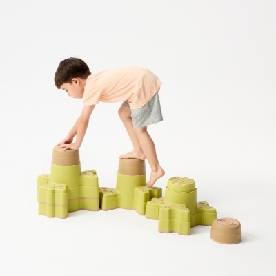 Brinquedo modular de blocos verdes e castanhos com uma criança a brincar.