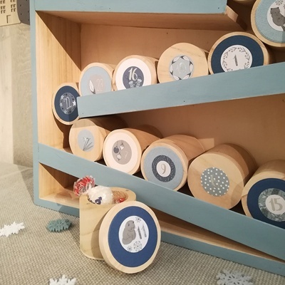 Rolos de madeira numerados em caixa azul e bege com designs variados.