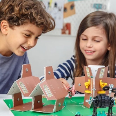 Crianças a brincar com casas e peças de construção de cartão e plástico colorido