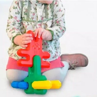 Criança a brincar com blocos de montar coloridos sentado no chão