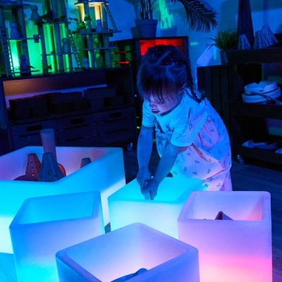 Menina a brincar com cubos iluminados coloridos num ambiente interior