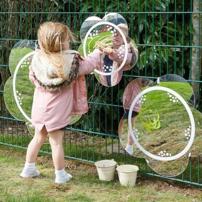 Espelho de parede em forma de flor refletindo criança e relva