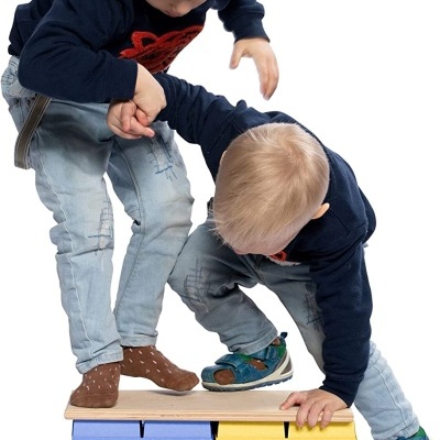 Duas crianças brincam em móvel com cubos coloridos e tampo de madeira