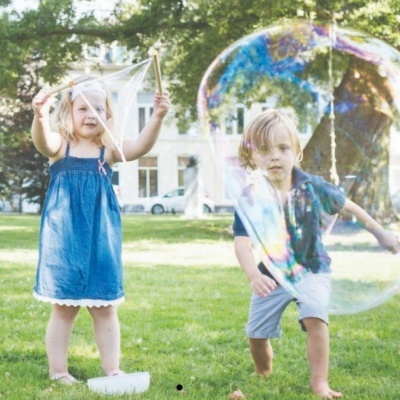 Duas crianças brincando com bolhas de sabão num parque