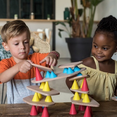 Crianças brincam com jogo de equilíbrio feito de cones coloridos e placas de madeira