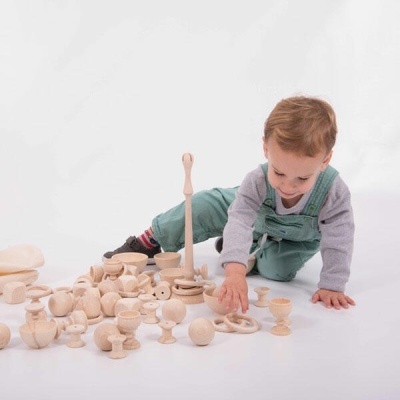 Criança brincando com brinquedos de madeira no chão branco