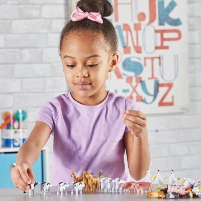 Menina a brincar com miniaturas de animais de fazenda