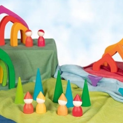 Brinquedos de madeira coloridos com figuras cónicas e formas geométricas sobre tecidos.