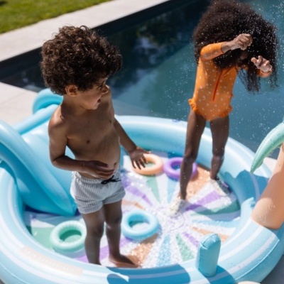 Piscina insuflável azul claro com argolas coloridas e crianças a brincar
