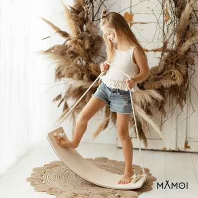 Criança a brincar com prancha de equilíbrio de madeira em ambiente interior decorado.