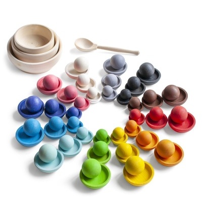 Peças de madeira coloridas com bolas e bases, tigelas e colher em madeira natural