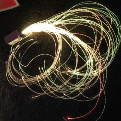 Fios de luzes de fibra ótica coloridas formando padrões circulares em fundo escuro